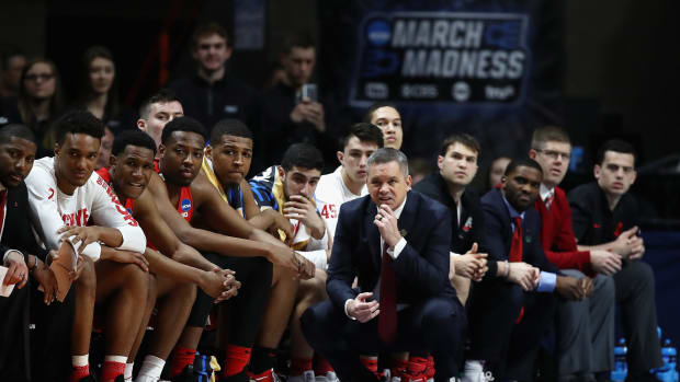 Ohio State basketball coach Chris Holtmann squatting on the sideline.